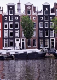 Sailboats moored on canal by buildings in city
