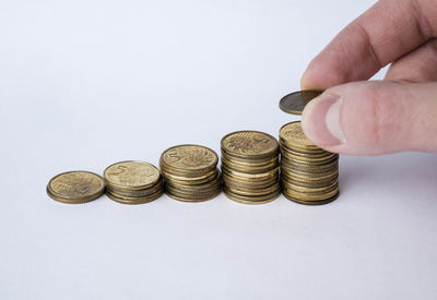 Close-up of hand holding coins on white background