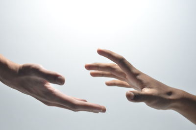 Close-up of hands against sky over white background