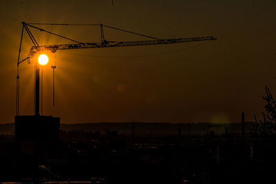 Silhouette of street lights against orange sky