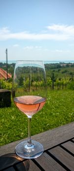 Close-up of wineglass on table against sky