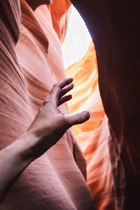 Cropped hand of woman gesturing against canyon