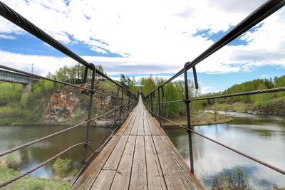 Footbridge over river against sky