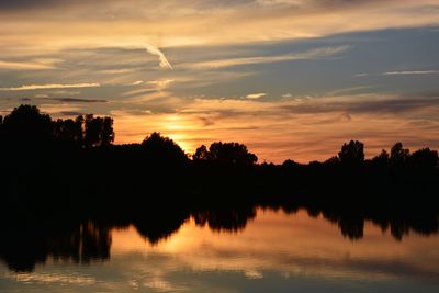 Reflection of trees in lake during sunset