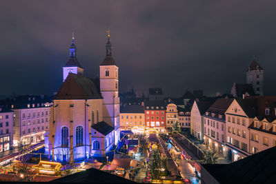 Illuminated buildings in city against sky at night