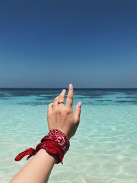 Cropped hand of woman against sea