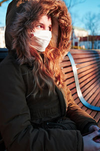 Portrait of woman sitting on seat in winter