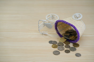 Coins in toy bicycle basket on wooden table