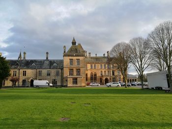 Lawn in front of building against cloudy sky