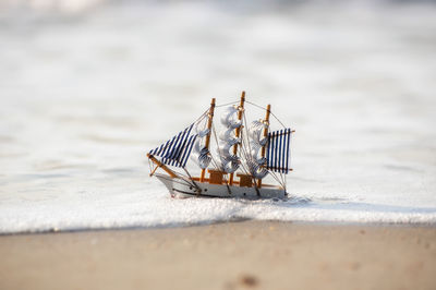 Close-up of deck chairs on table at beach boat at sea