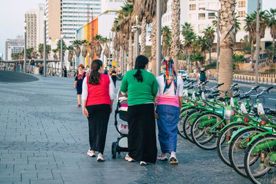 Rear view of people walking on road in city