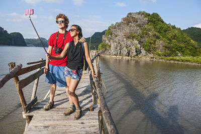 Young couple taking selfie on boardwalk in vietnam's halong bay