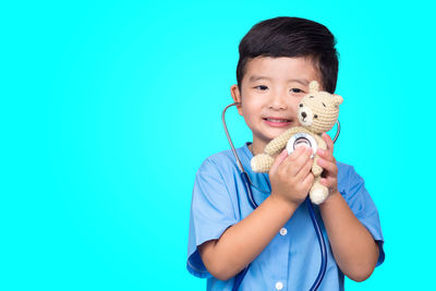 Portrait of smiling boy holding blue background