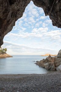 Rock formation by sea against sky