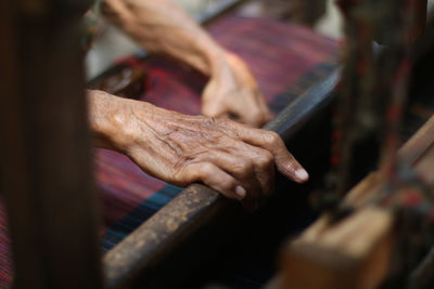 Cropped hands of senior person working at textile industry