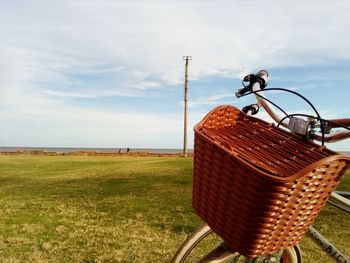 Close-up of wicker basket on field against sky