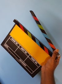 Cropped image of person holding film slate against wall