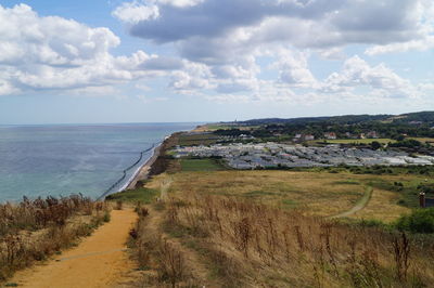 Scenic view of land by sea against sky