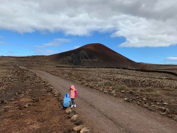 Woman with umbrella on mountain against sky