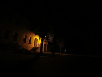 Illuminated street light by building at night