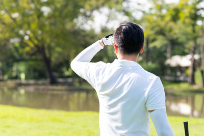 Rear view of mid adult man standing at golf course