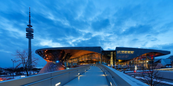 Illuminated buildings in city against cloudy sky