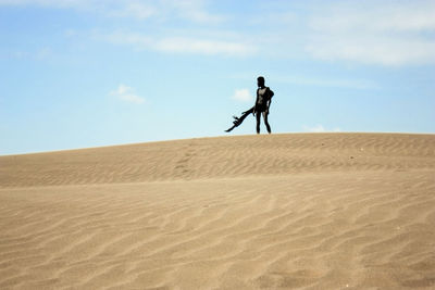 Teenage boy in costume on desert against sky