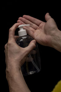 Close-up of hand holding drink against black background