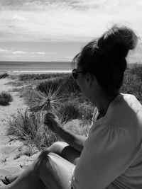 Close-up of girl sitting at beach against sky