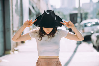 Midsection of woman holding hat while standing outdoors