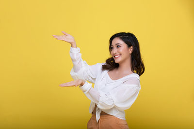 Portrait of a smiling young woman against yellow background