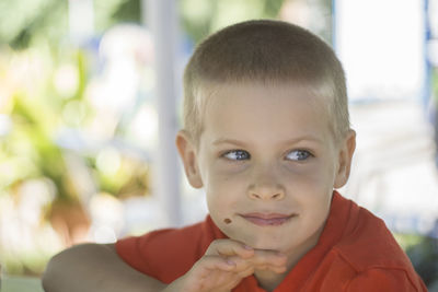 Close-up of boy with hand on chin looking away outdoors