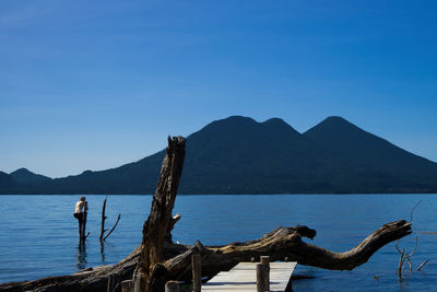 Man standing by sea against clear blue sky