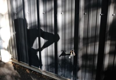 Tap on metallic fence with shadow of person