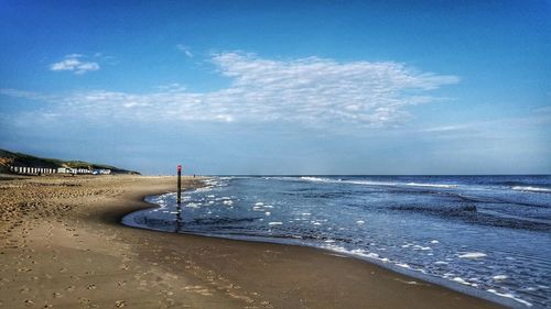 Scenic view of beach against cloudy sky