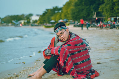 Rear view of man sitting on beach