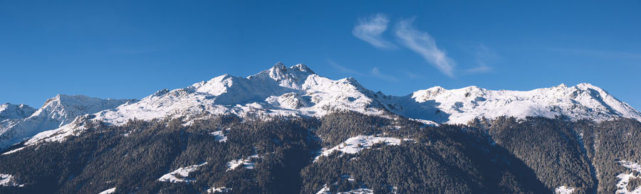 Low angle view of snowcapped mountains against blue sky