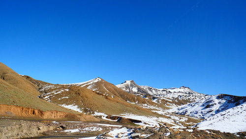 Scenic view of snowcapped mountains against clear blue sky