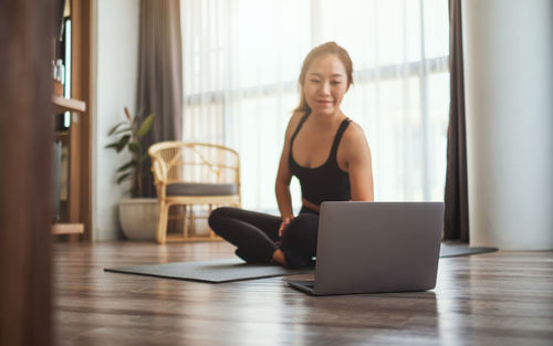 Young woman using laptop while sitting on table