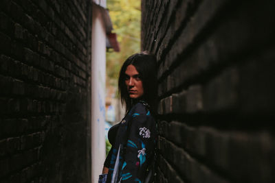 Side view portrait of young woman standing against wall