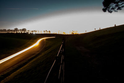 Light trails on road against sky at night