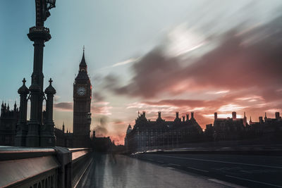 Blurred motion of people on westminster bridge by big ben against sky during sunset