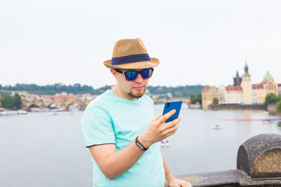 Man using mobile phone in city against sky