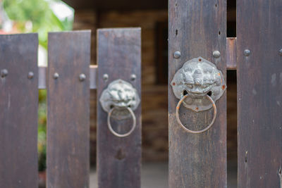 Close-up of metal gate against fence