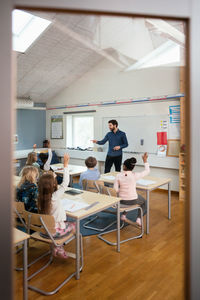 Teacher asking to students seen from entrance of classroom