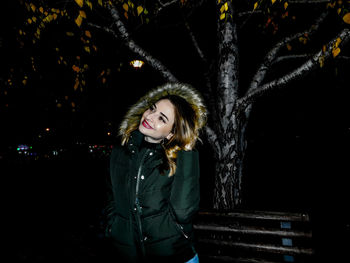 Smiling woman in warm clothing standing at night