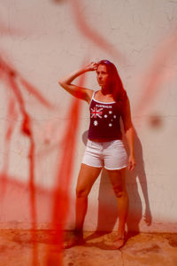 Portrait of young woman standing against wall