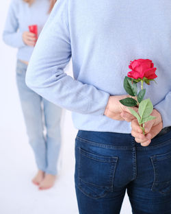 Young attractive man holding a rose behind his back to surprise his lover.