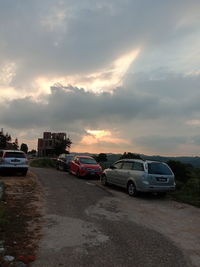 Cars on road against sky during sunset