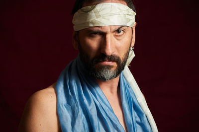 Portrait of man wearing headscarf against black background